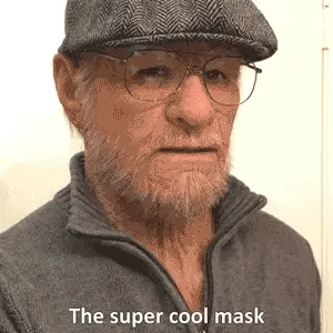 Older-character mask worn with glasses and a flat cap