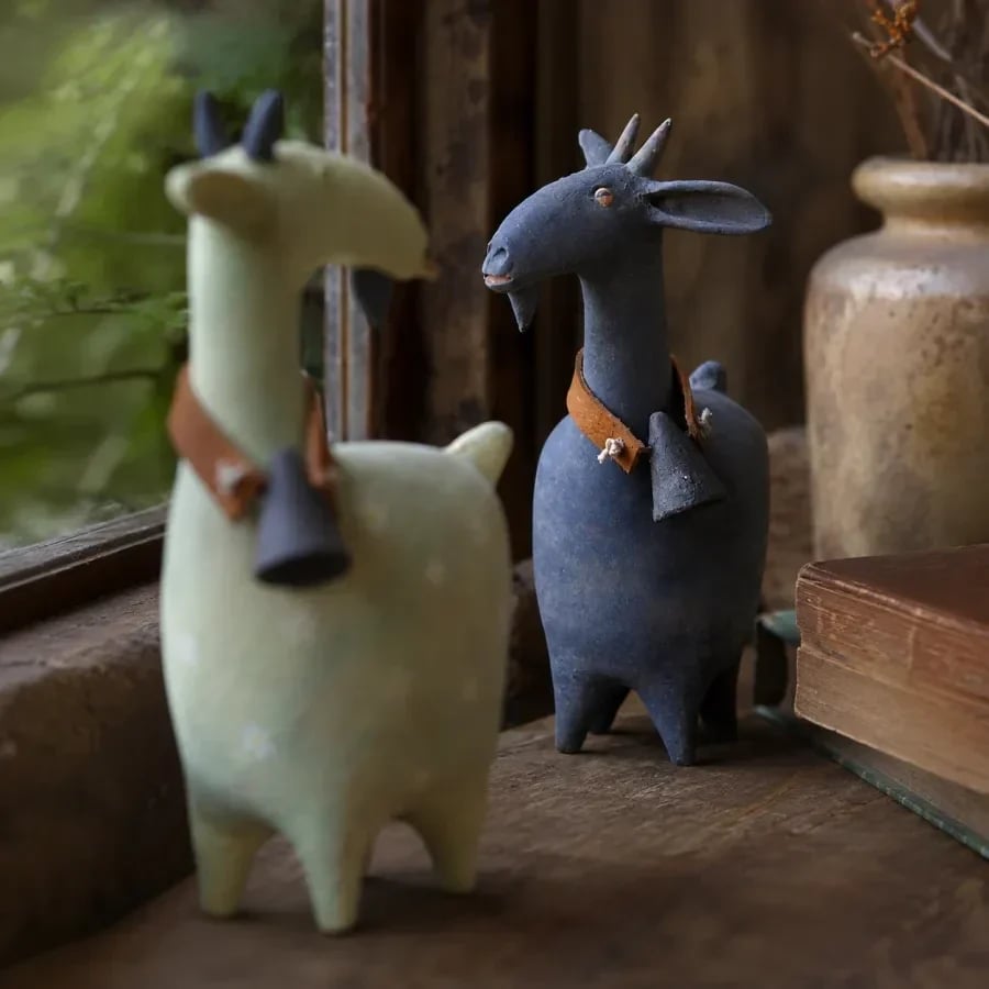 Close styled photo of whimsical goat figurines by a window