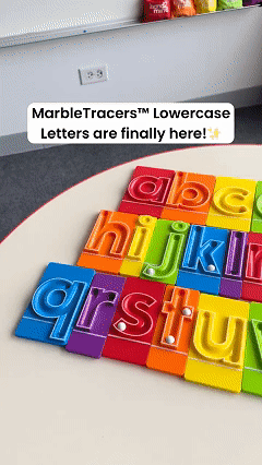 Child rolling marble through lowercase letter tray