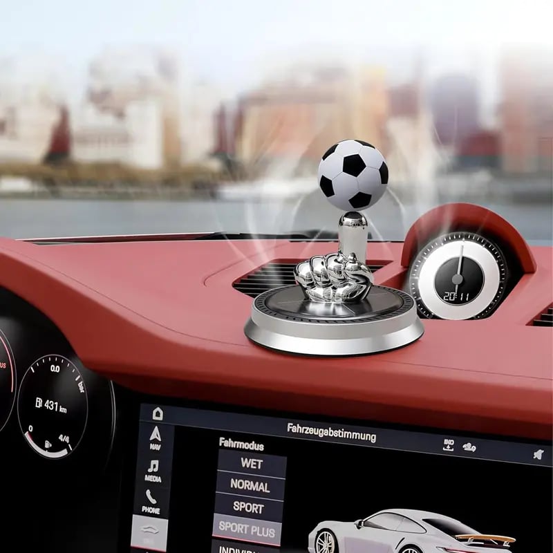 Silver rotating soccer ornament displayed on a car dashboard